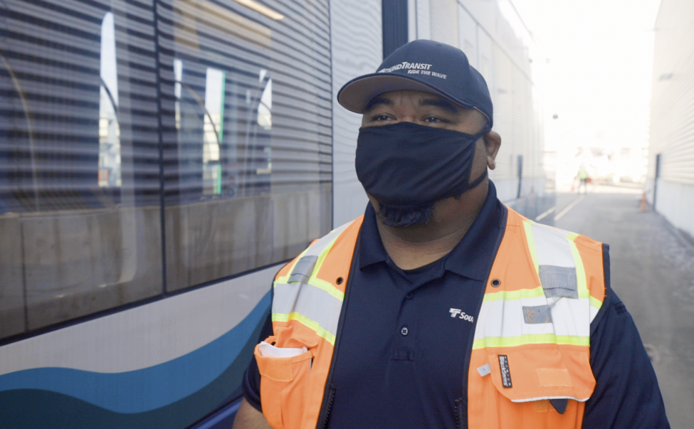 A Tacoma Link operator walks next to the train.