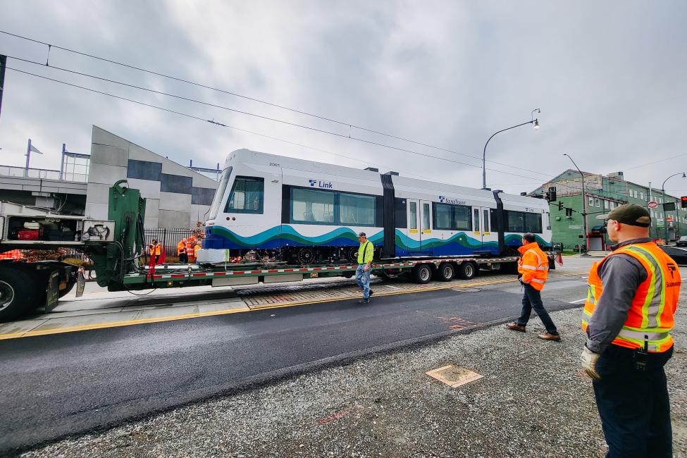 Workers watch the new light rail vehicle arrive in downtown Tacoma.