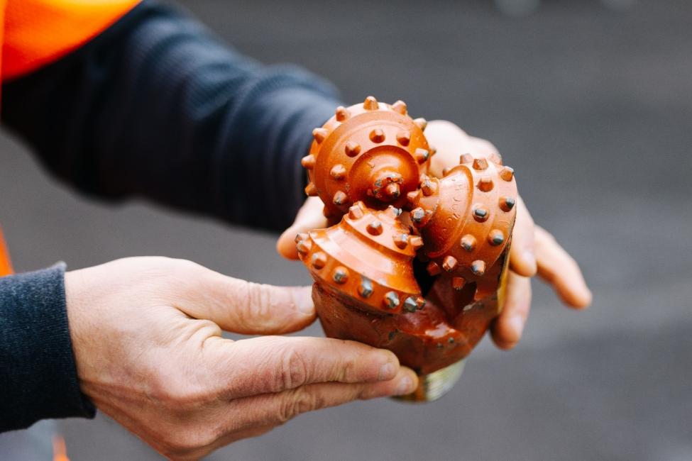 An engineer holds a Geotech boring rig’s drill bit.