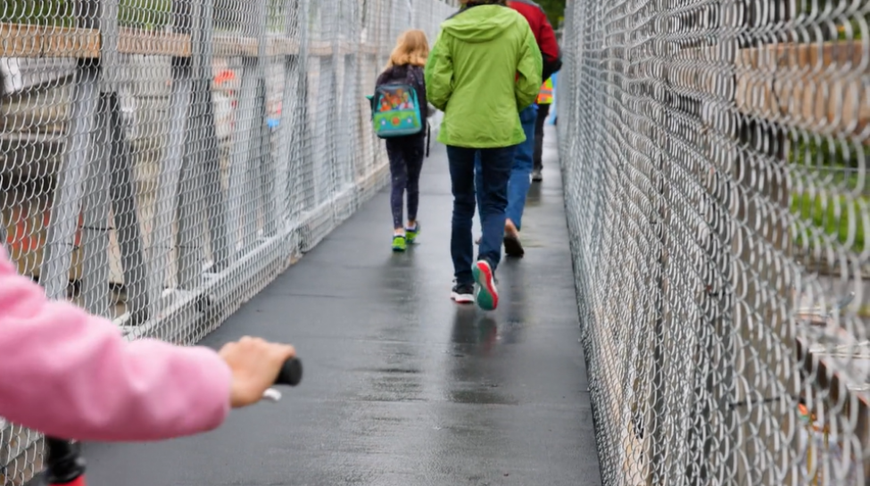 Kids walk and bike across a bridge.