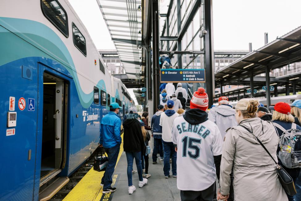 A crowd wearing Mariners gear departs a Sounder train at King Street Station.