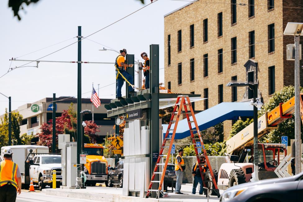 Crews stand on top of a station while installing an art piece.