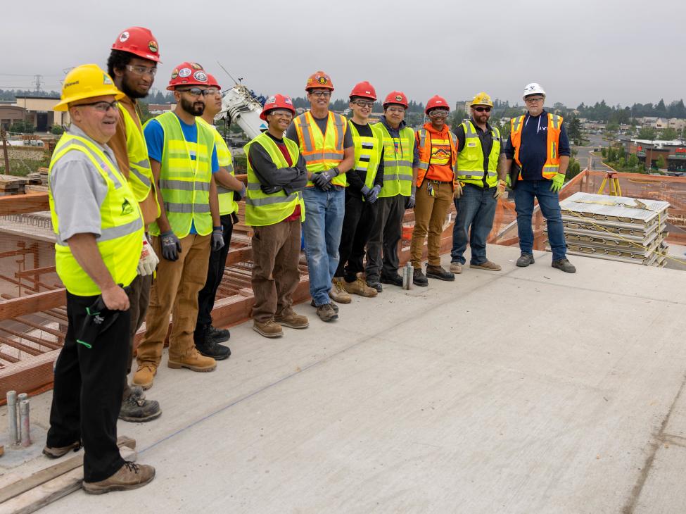 A group photo of people wearing construction gear, including vests and hard hats.