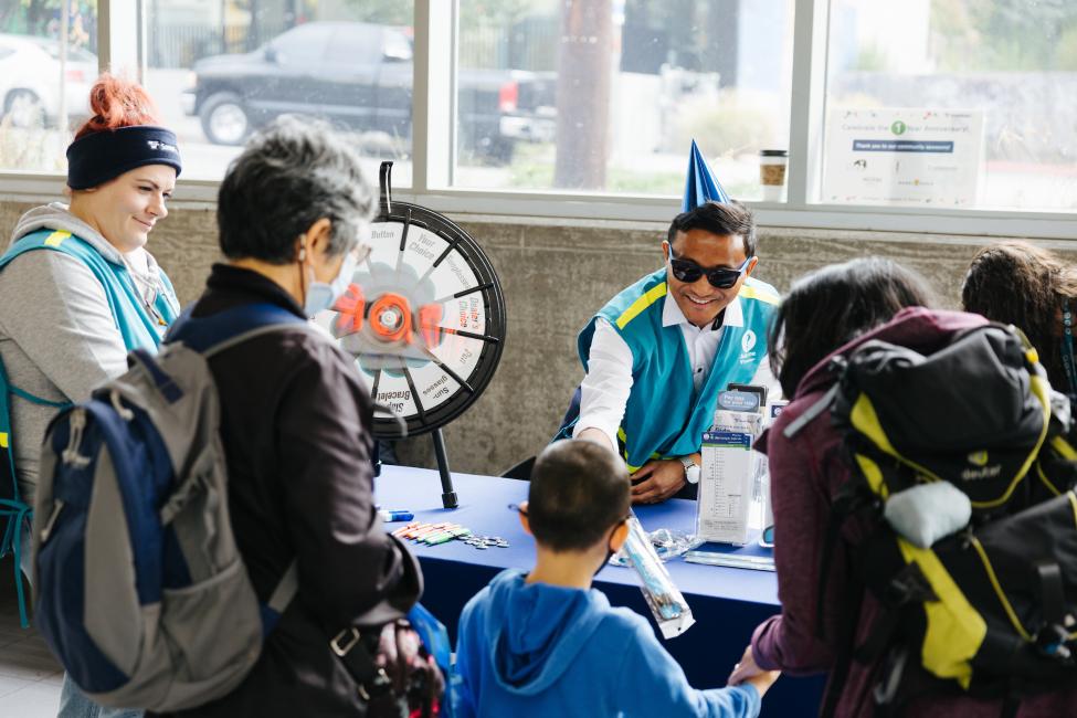 People sign a banner and spin a giveaway wheel at Roosevelt Station.