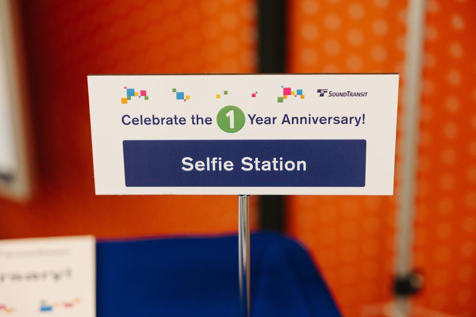 A sign says 'Celebrating the 1 line anniversary' and 'Selfie Station.'