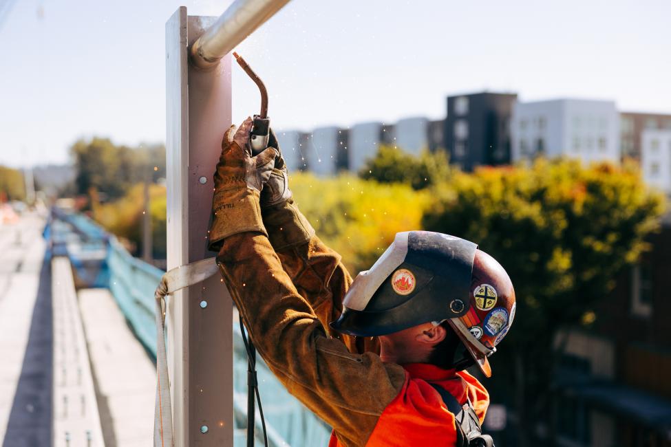 A worker in a full face mask welds an element on the light rail platform. 