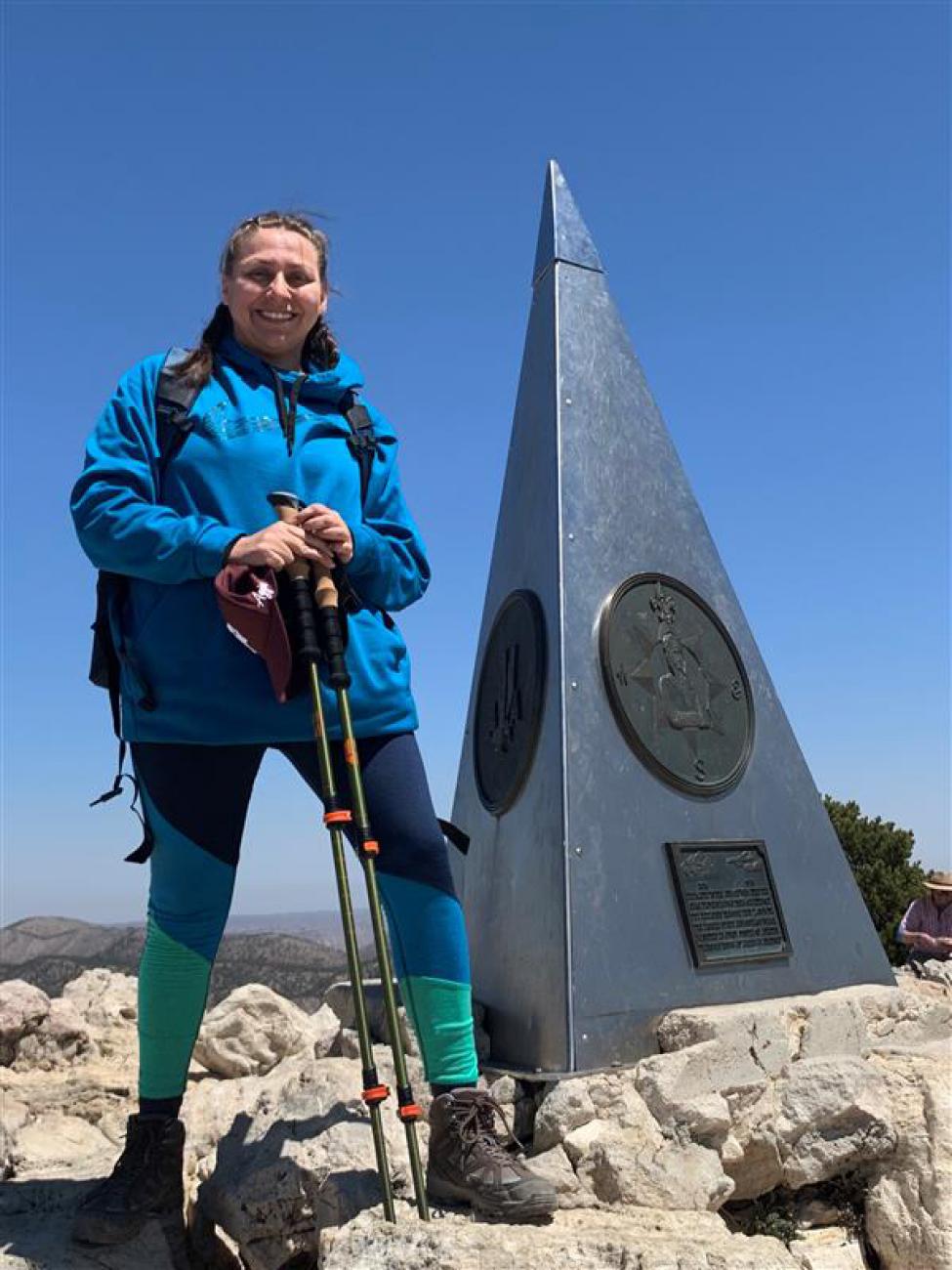 Valerie Valero stands on top of a mountain peak.