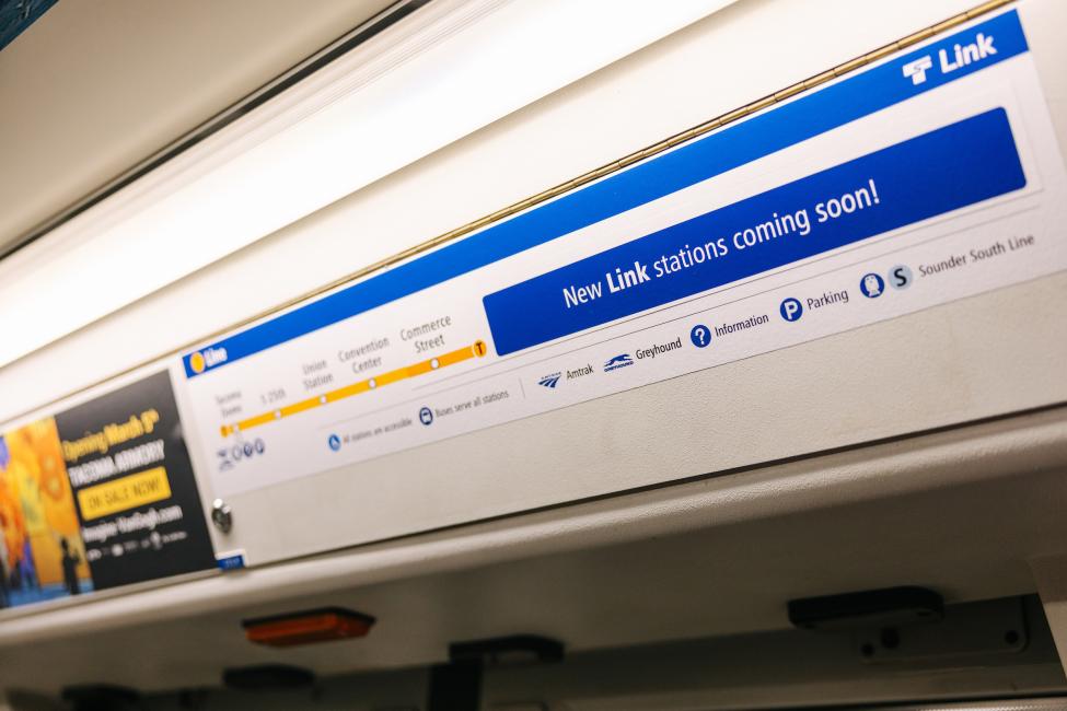 A sign on the inside of a T Line vehicle reads "New stations opening soon!"