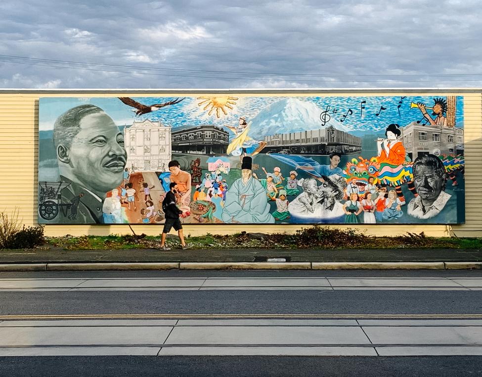 A person walks by a mural in Tacoma depicting Martin Luther King Jr and other historical figures. 