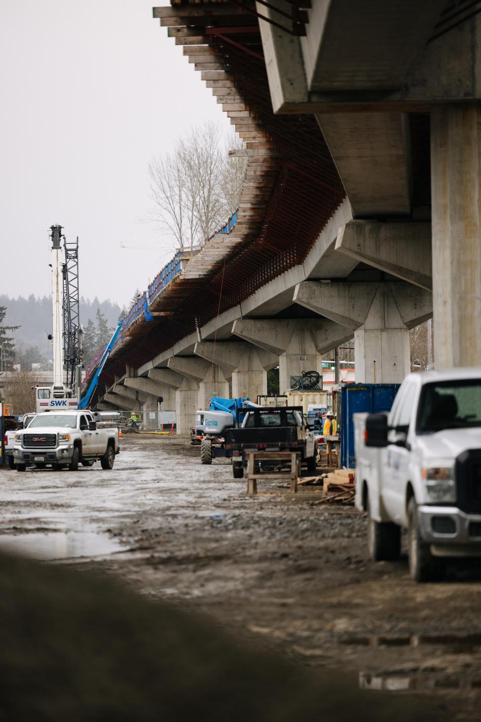 A white truck is parking under elevated guideway for light rail.