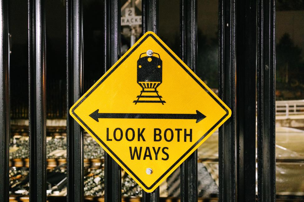 A yellow sign with a train on it. Text reads 'look both ways.'