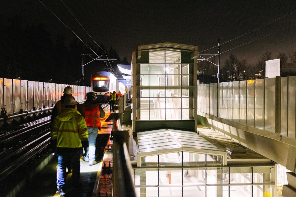 Crews walk along a light rail platform in Bellevue at night. 