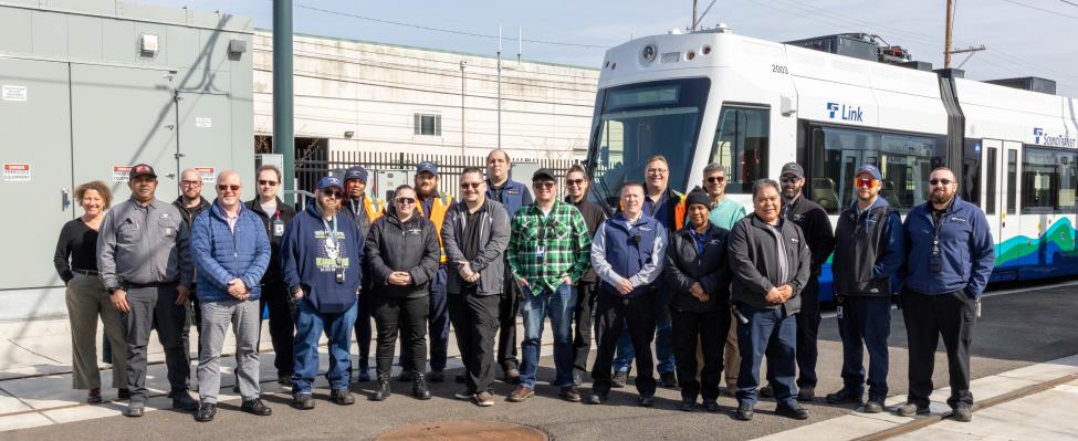 A group photo of people in front of a T Line car