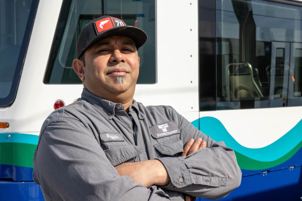 An operator poses with arms crossed in front of a T Line train