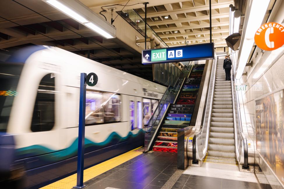 People ride an escalator up to the mezzanine at University Street Station.