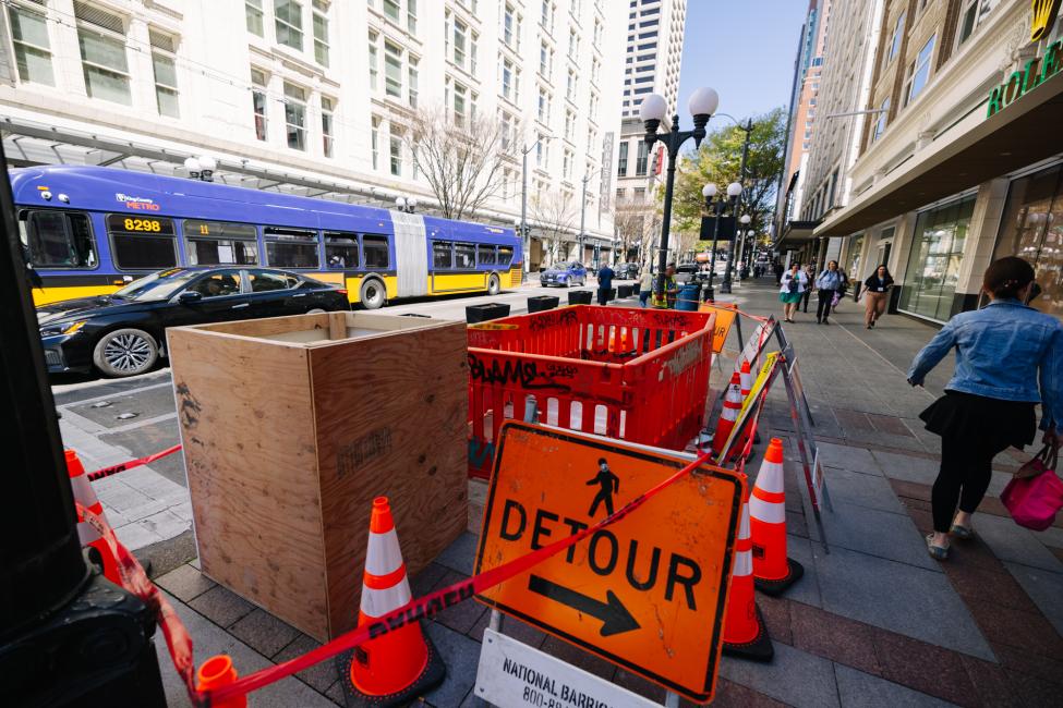 A detour sign and orange barricades around the hole above Westlake Station