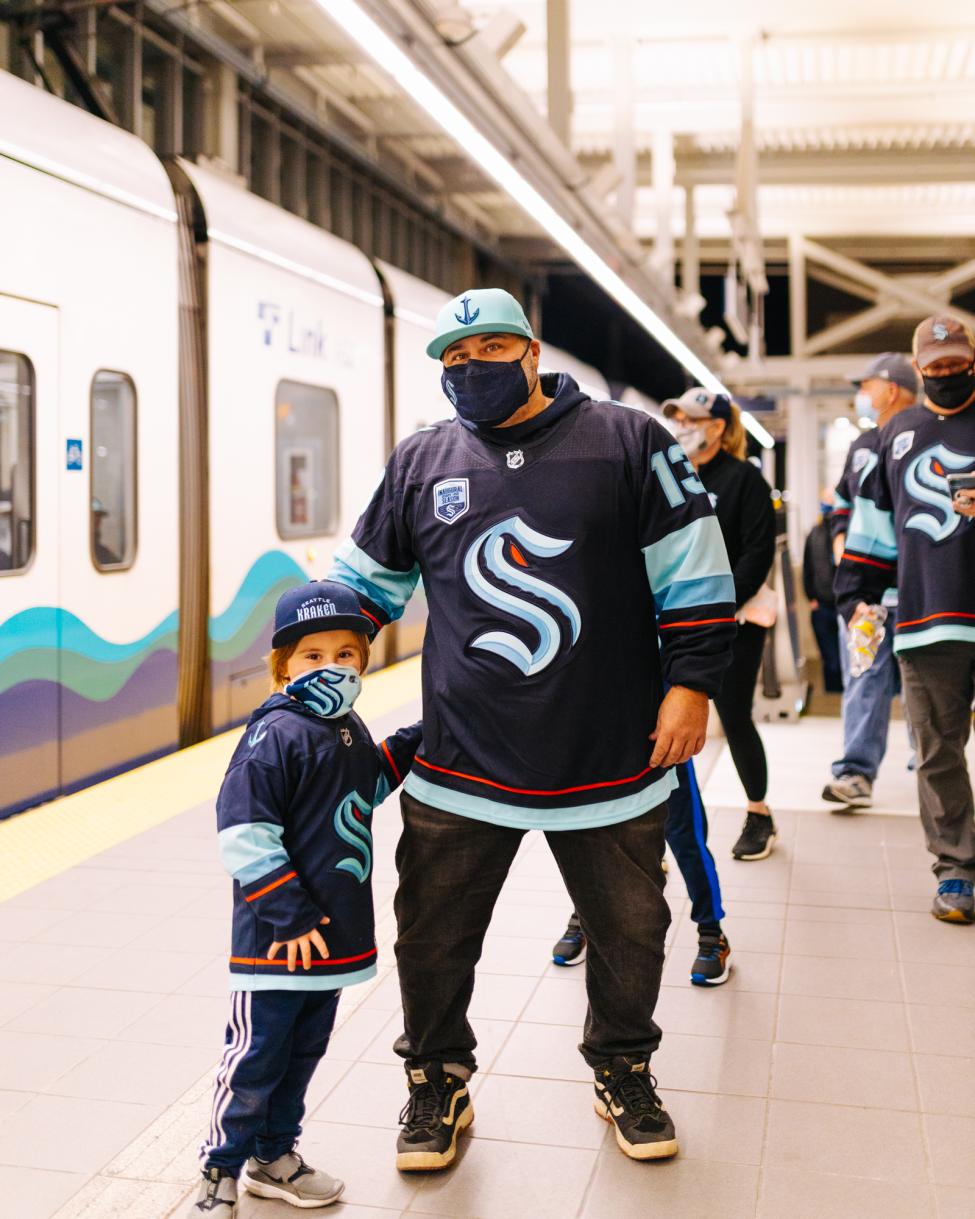 A father and son in Kraken jerseys on a Link platform