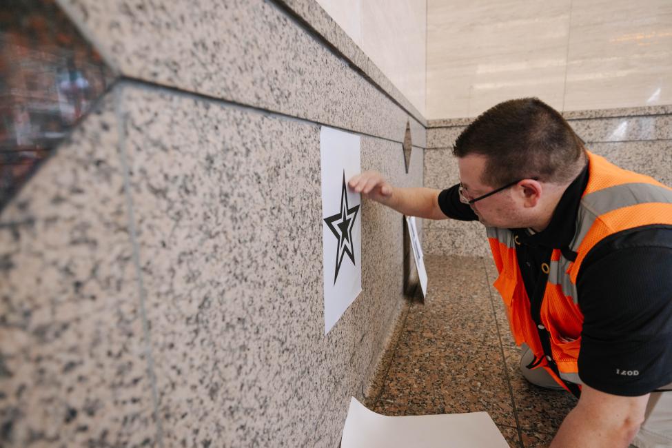 An ST employee installs a star decal on the wall of Westlake Station