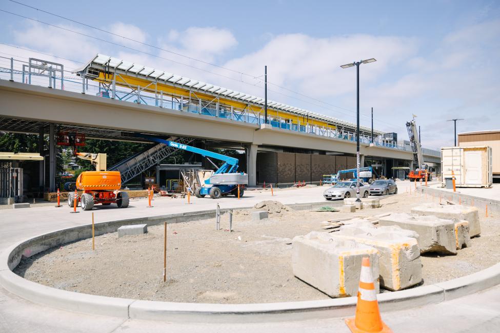 Construction equipment is parked by a light rail station