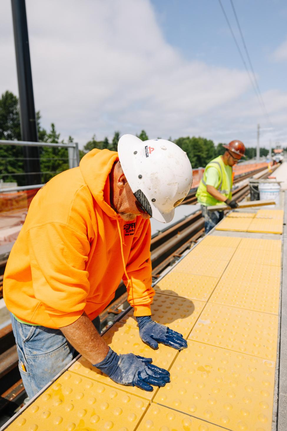 Workers lay the yellow tiles on a train platform