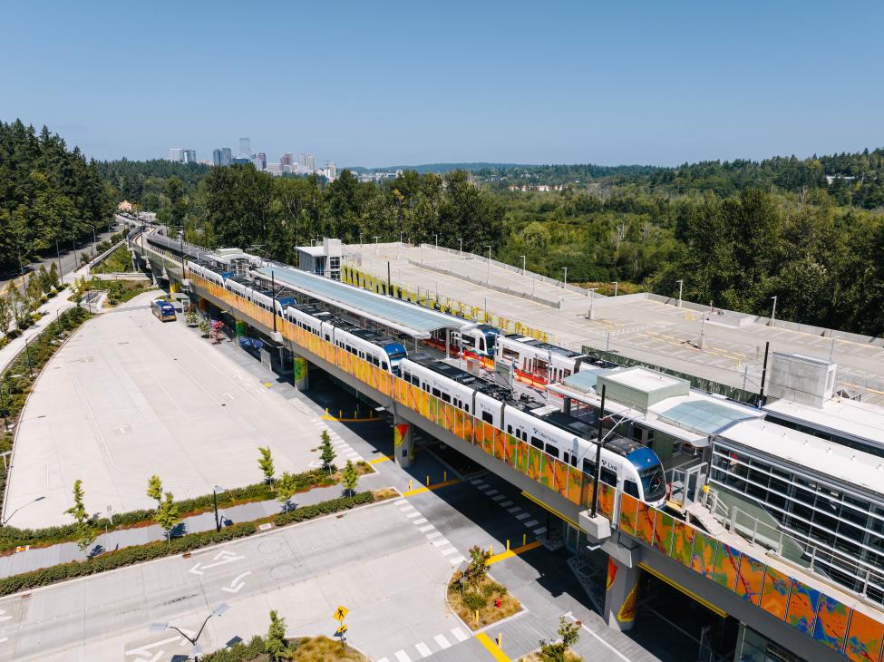 Link trains at the South Bellevue Station on a sunny day, with trees and downtown Bellevue in the background