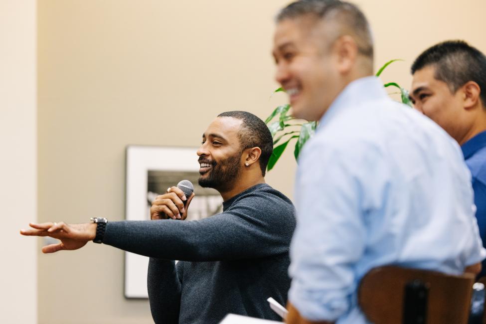 Doug Baldwin holds a microphone in one hand and gestures to the crowd with the other