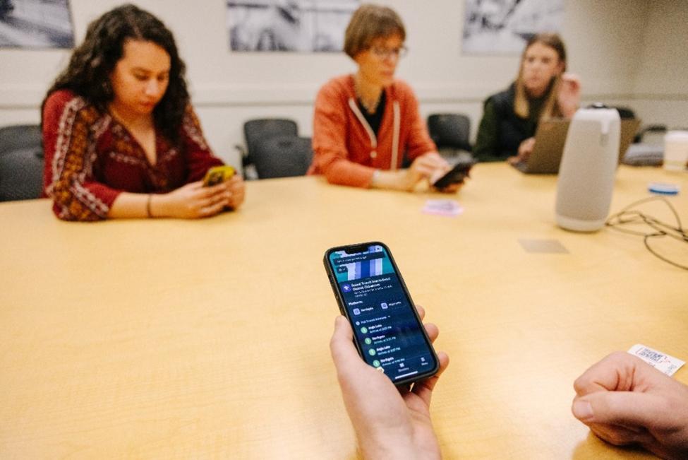 People sit around a conference table using their smartphones.