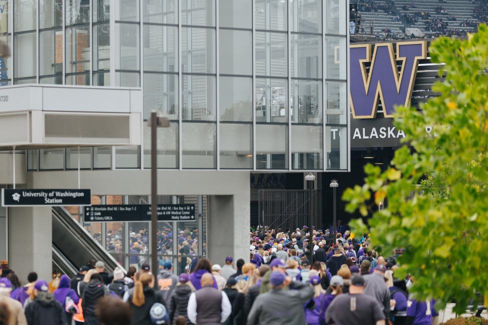 Fans dressed in purple file into Husky Stadium.