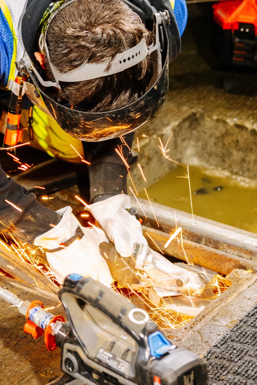 A worker in a full face mask welds an element in the light rail tunnel