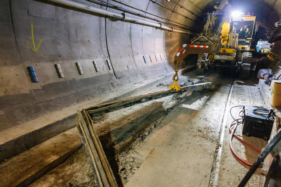 A piece of heavy machinery helps workers replace rail in the tunnel