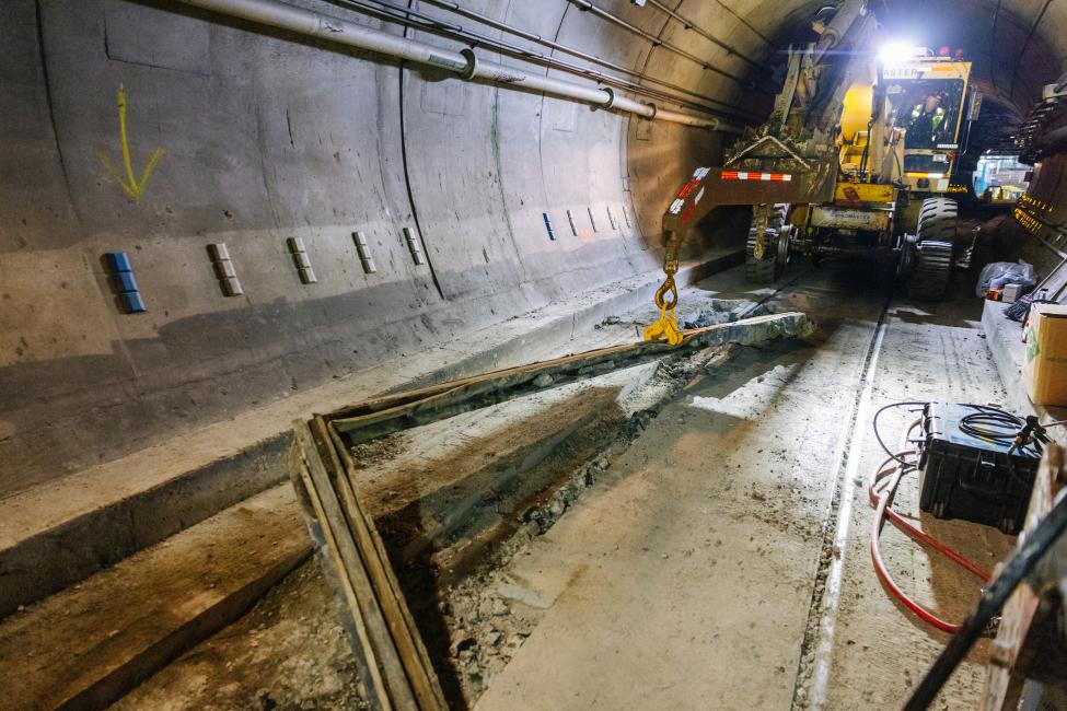 A piece of heavy machinery helps workers replace rail in the tunnel