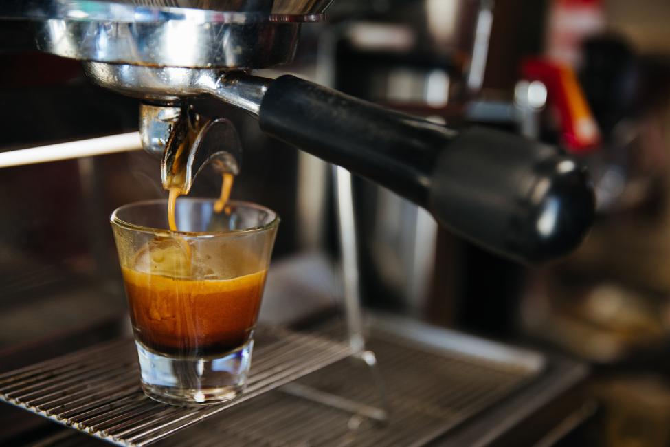 A shot of espresso is poured into a small glass 