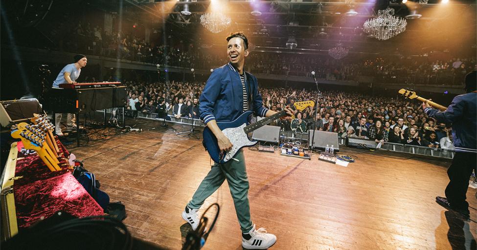 Cory Wong with his guitar on stage in front of an engaged crowd.