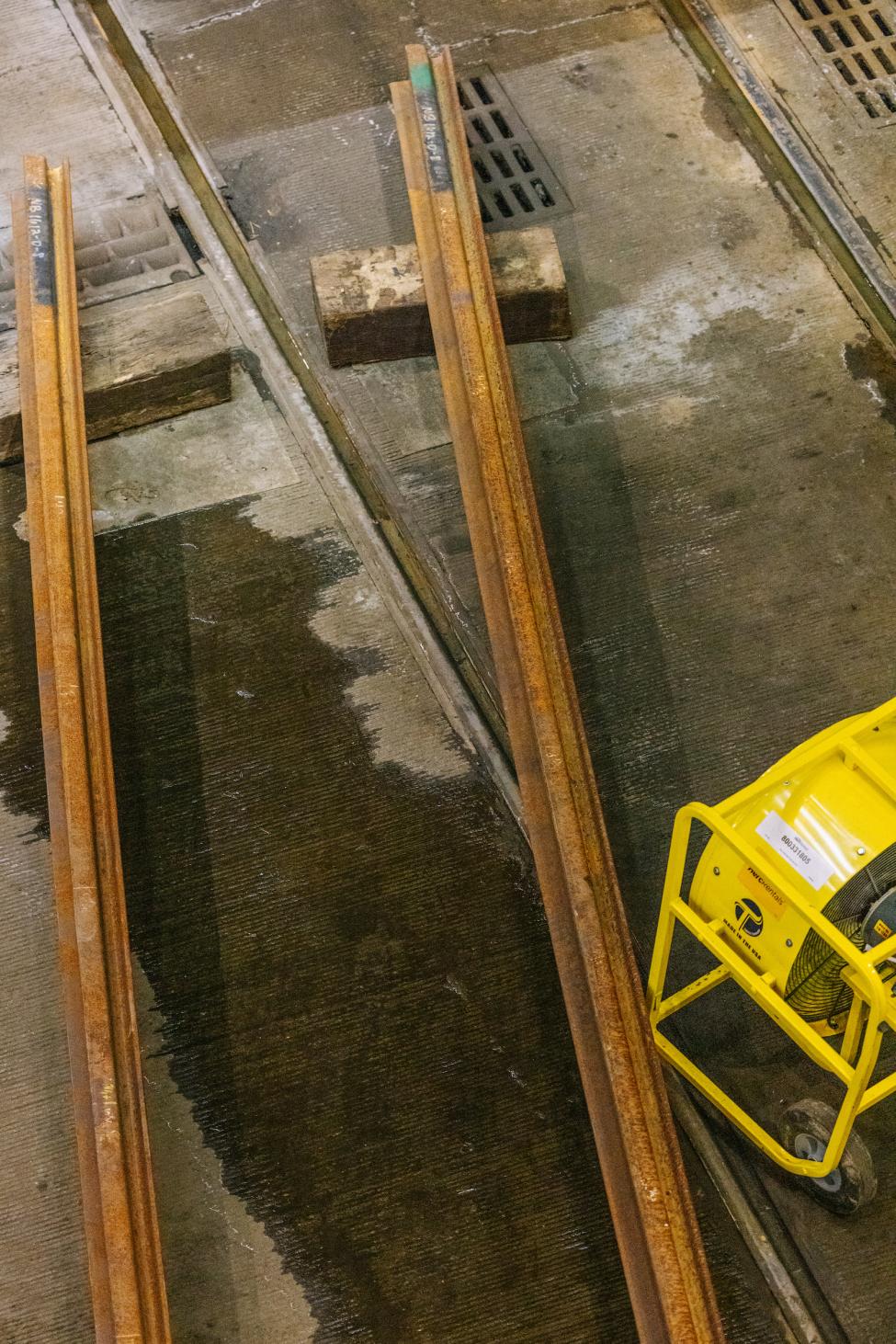 A piece of construction equipment and two rail lengths photographed from above