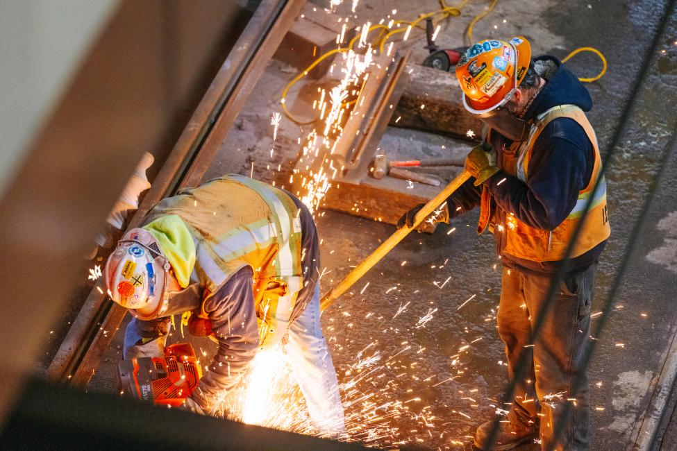 Sparks fly as construction workers in protective gear work in the downtown transit tunnel