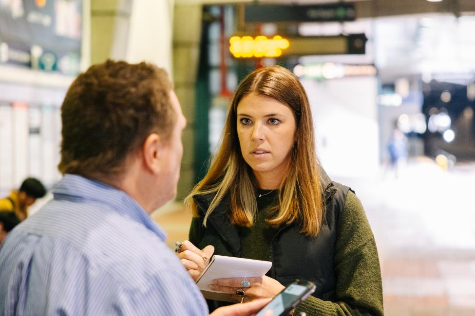 A GoodMaps tester talks to a passenger on the platform at Chinatown International District Station