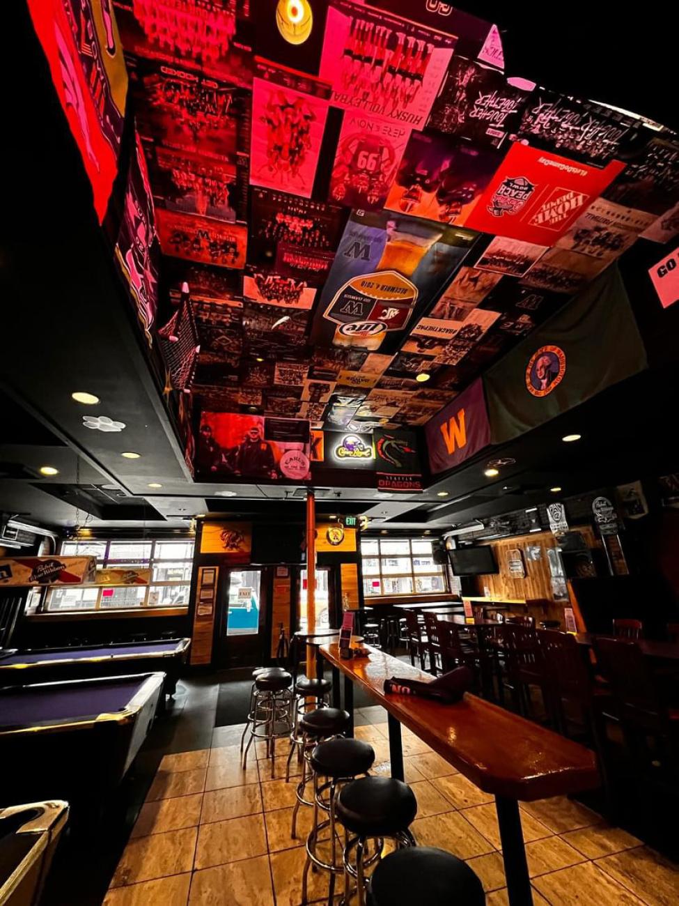 The interior of Earls on the Ave, with seating on the right, pool tables on the left and posters on the ceiling