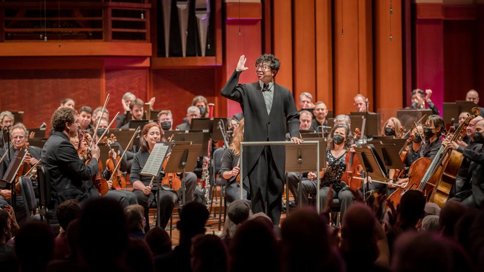 The Seattle Symphony performs energetically in a well-lit room.