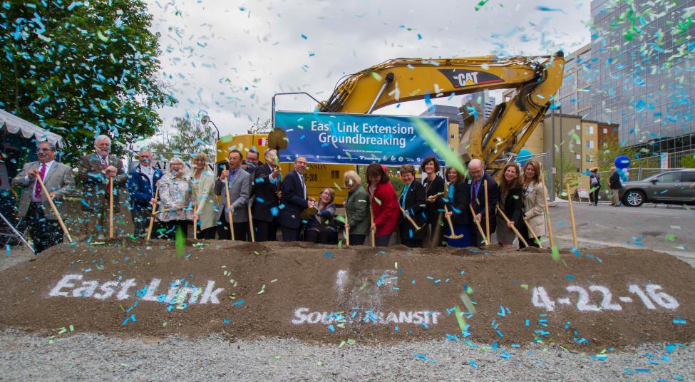 Confetti falls as a group of people shovel dirt in a ceremonial groundbreaking ceremony for East Link on April 22, 2016.