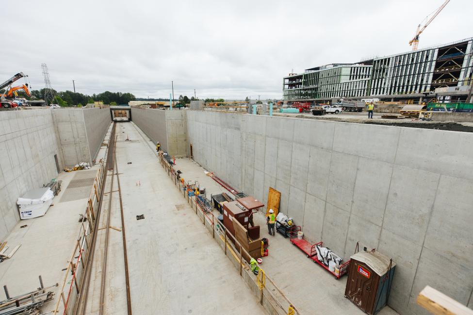 Looking down at the platform of Spring District Station, empty except for concrete and some construction fencing.