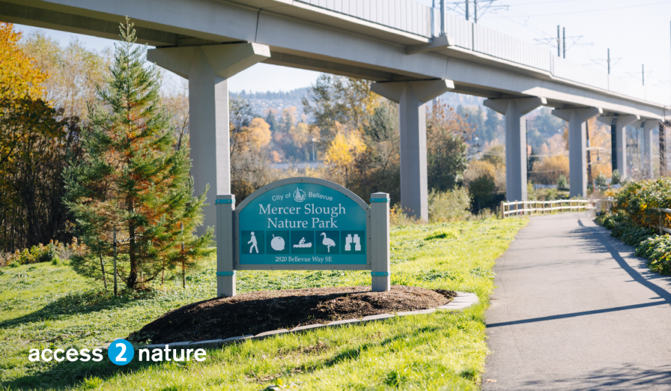 A sign for Mercer Slough Park in Bellevue, with elevated guideway for the light rail 2 Line extension in the background