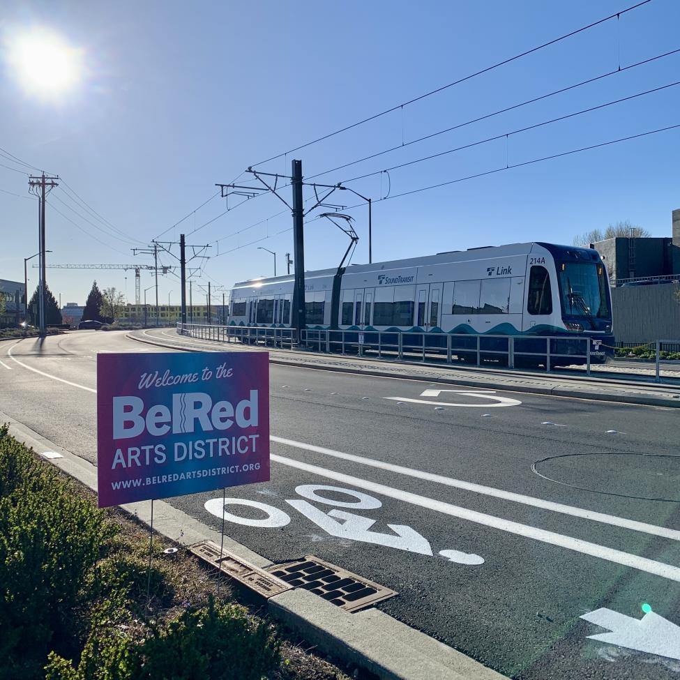 A 2 Line train runs on the street level, near a sign promoting the BelRed Arts District