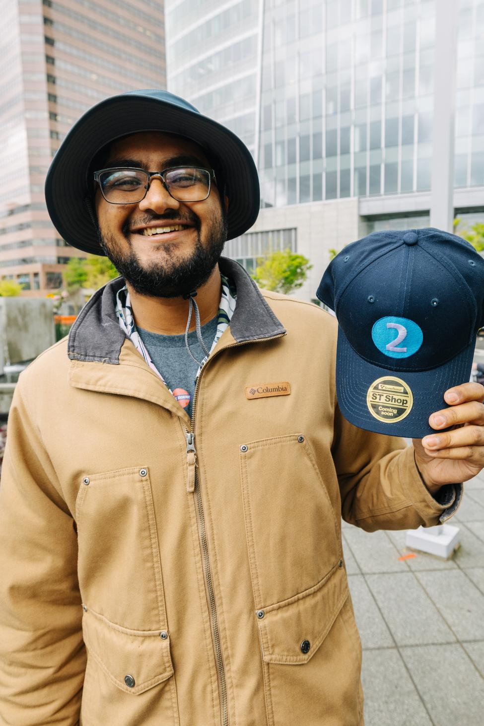 A passenger displays their commemorative 2-Line hat provided by HDR