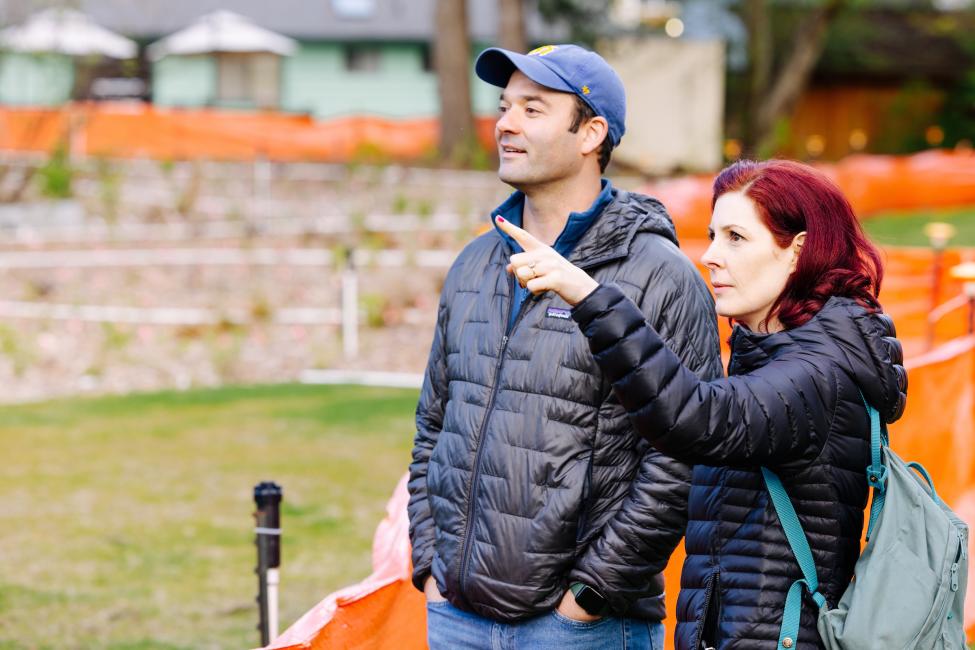 Two people in black jackets point out features of a park