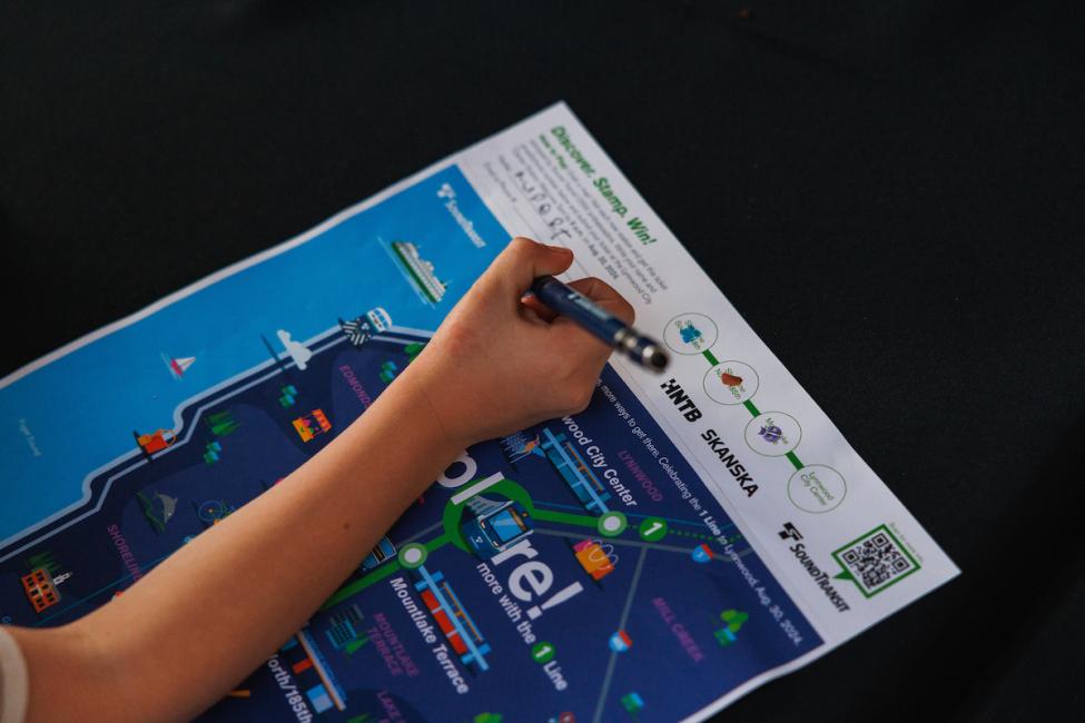 A passengers gets their commemorative Discover. Stamp. Win! map stamped by a Sound Transit ambassador