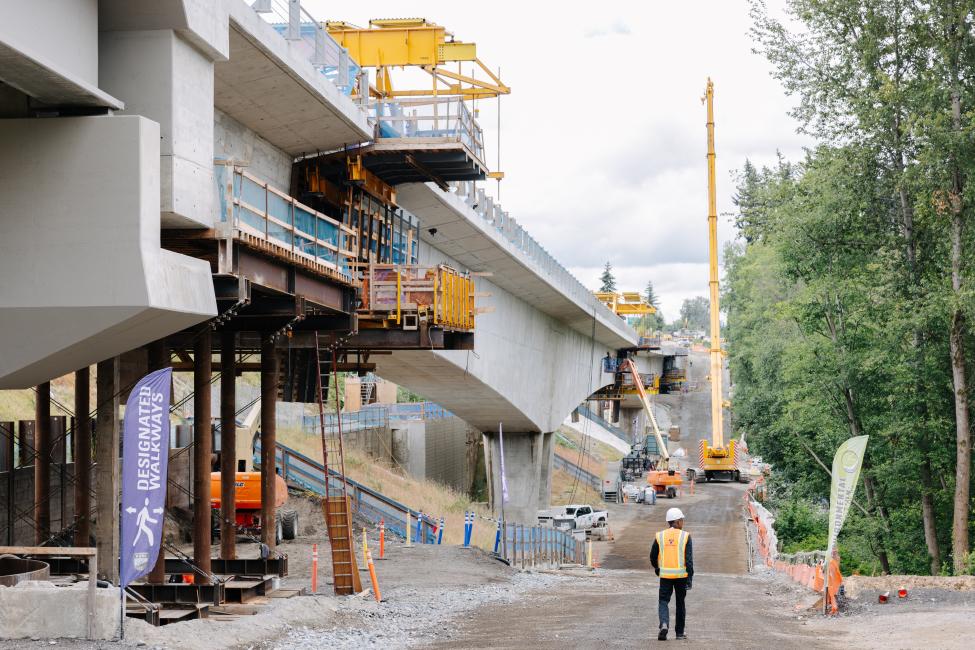 A worker walks to the left of a giant new light rail guideway under construction