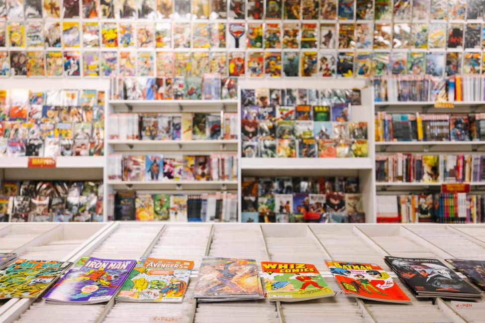 Comics line the walls of a shop, with more in boxes to browse