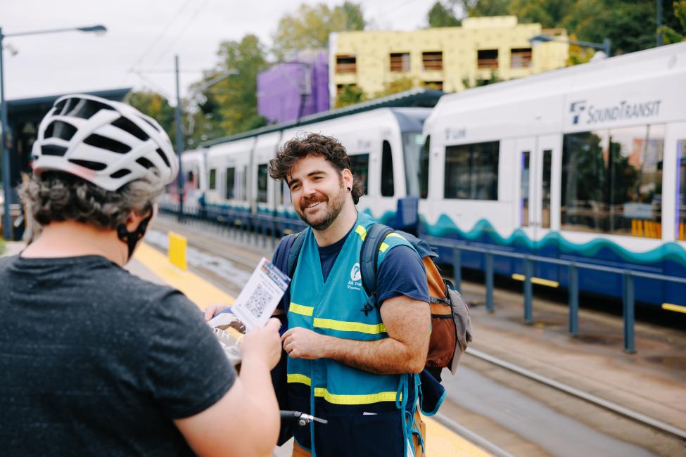 A Sound Transit staff ambassador helps a passenger at a Link station