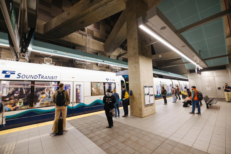People wait on the platform at U District Station as a Link train pulls in