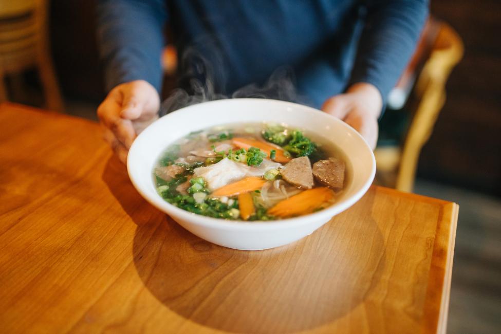 A steamy bowl of pho on a table